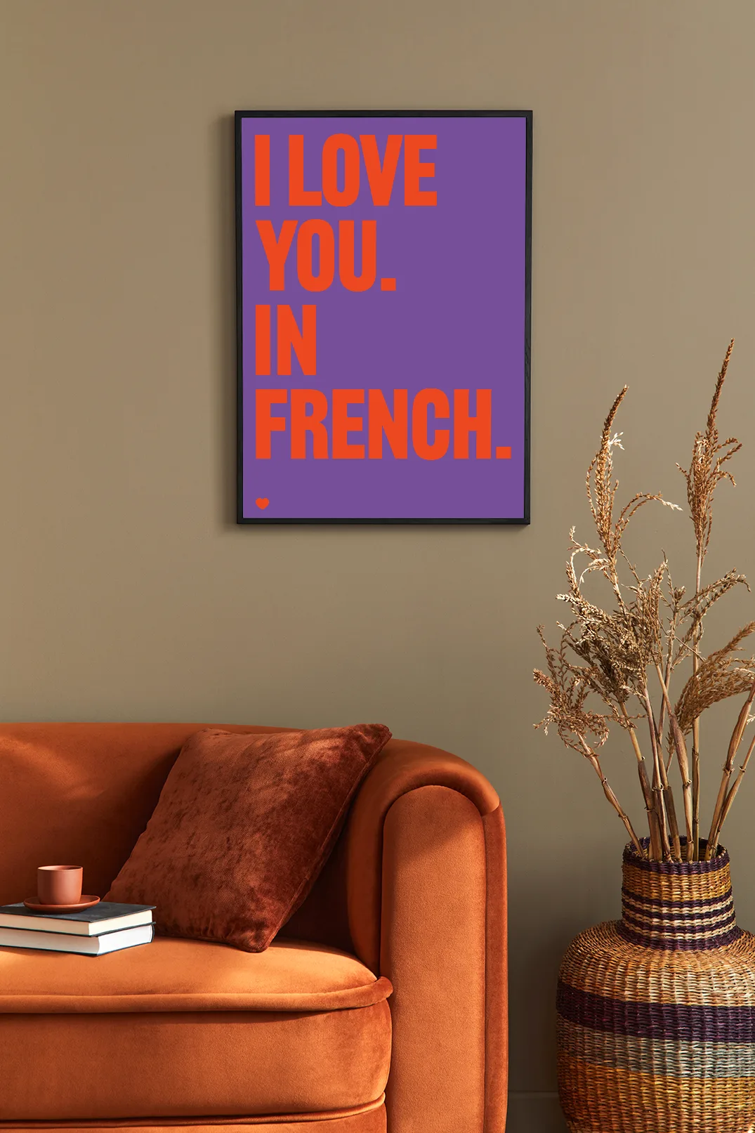 Woonkamer met oranje bank en poster I love you in french rood/paars